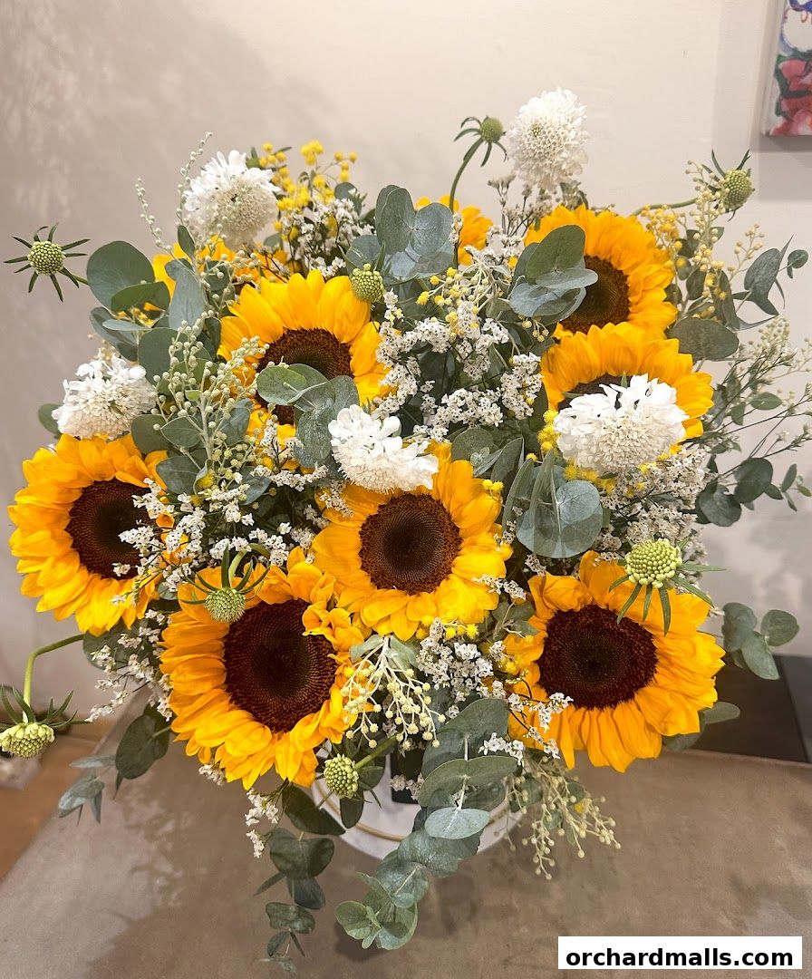 A vibrant bouquet of sunflowers with white and yellow filler flowers and eucalyptus leaves.