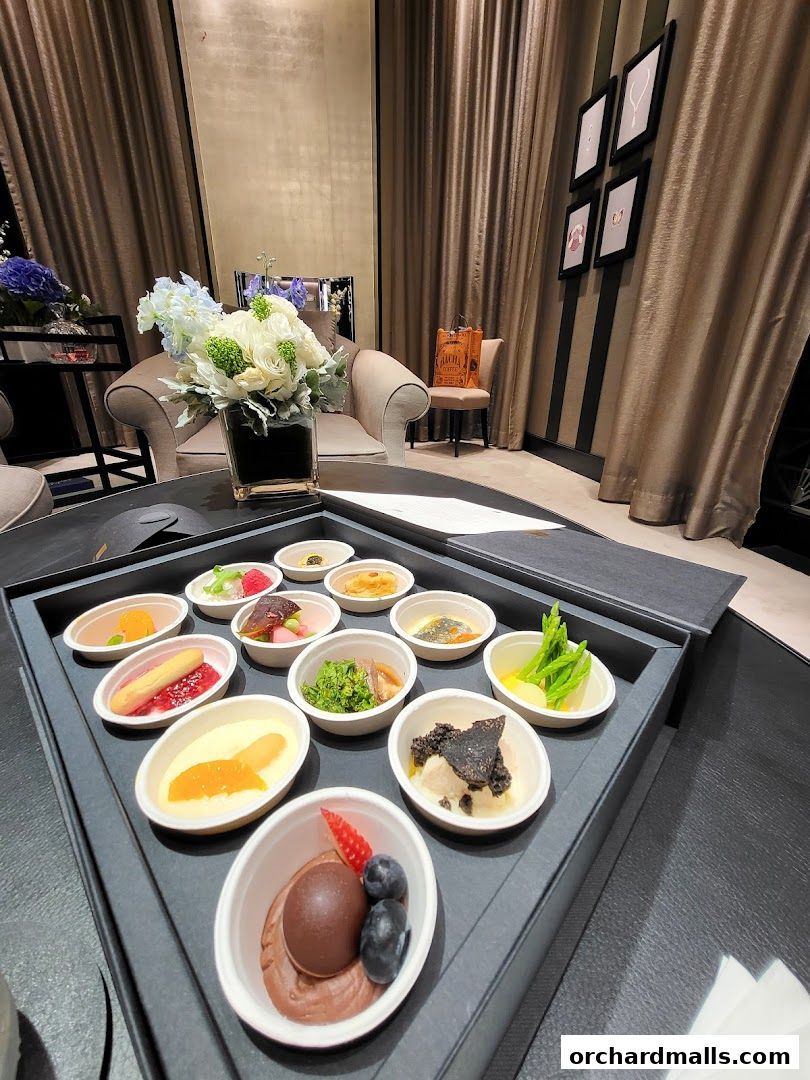 A tray of assorted small desserts and appetizers is presented in a luxurious setting.