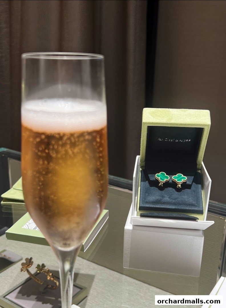 A glass of champagne next to a Van Cleef & Arpels jewelry box with earrings.