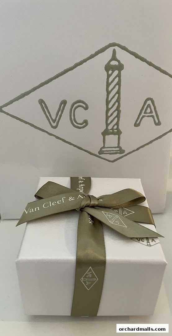 A white gift box with a green ribbon from Van Cleef & Arpels.
