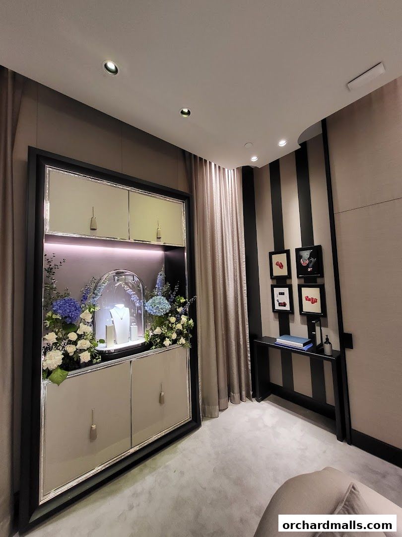 A display cabinet with jewelry and flowers, next to a console table with artwork.