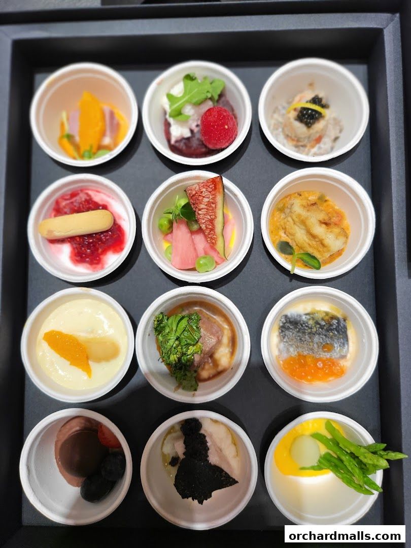 A tray of twelve small, individually portioned gourmet appetizers or desserts in white bowls.