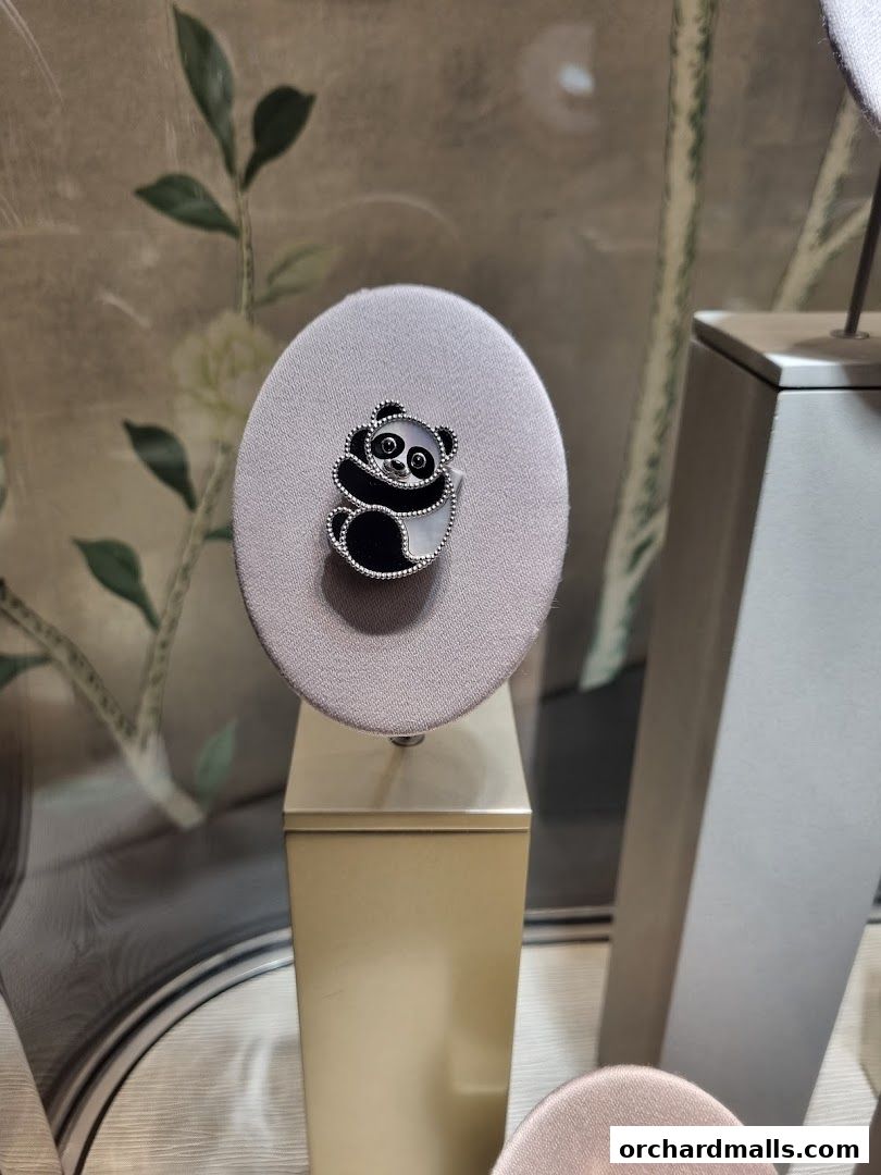 A charming panda-themed brooch displayed on a velvet stand in a luxury jewelry store.