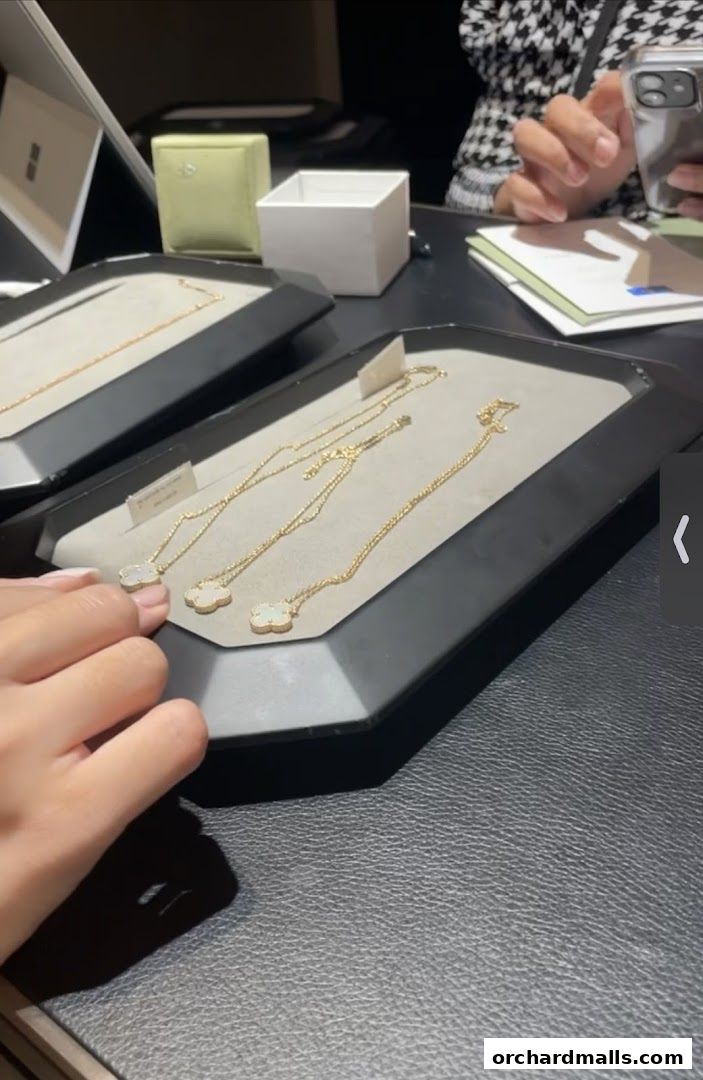 Close-up of Van Cleef & Arpels necklaces displayed on a black tray.