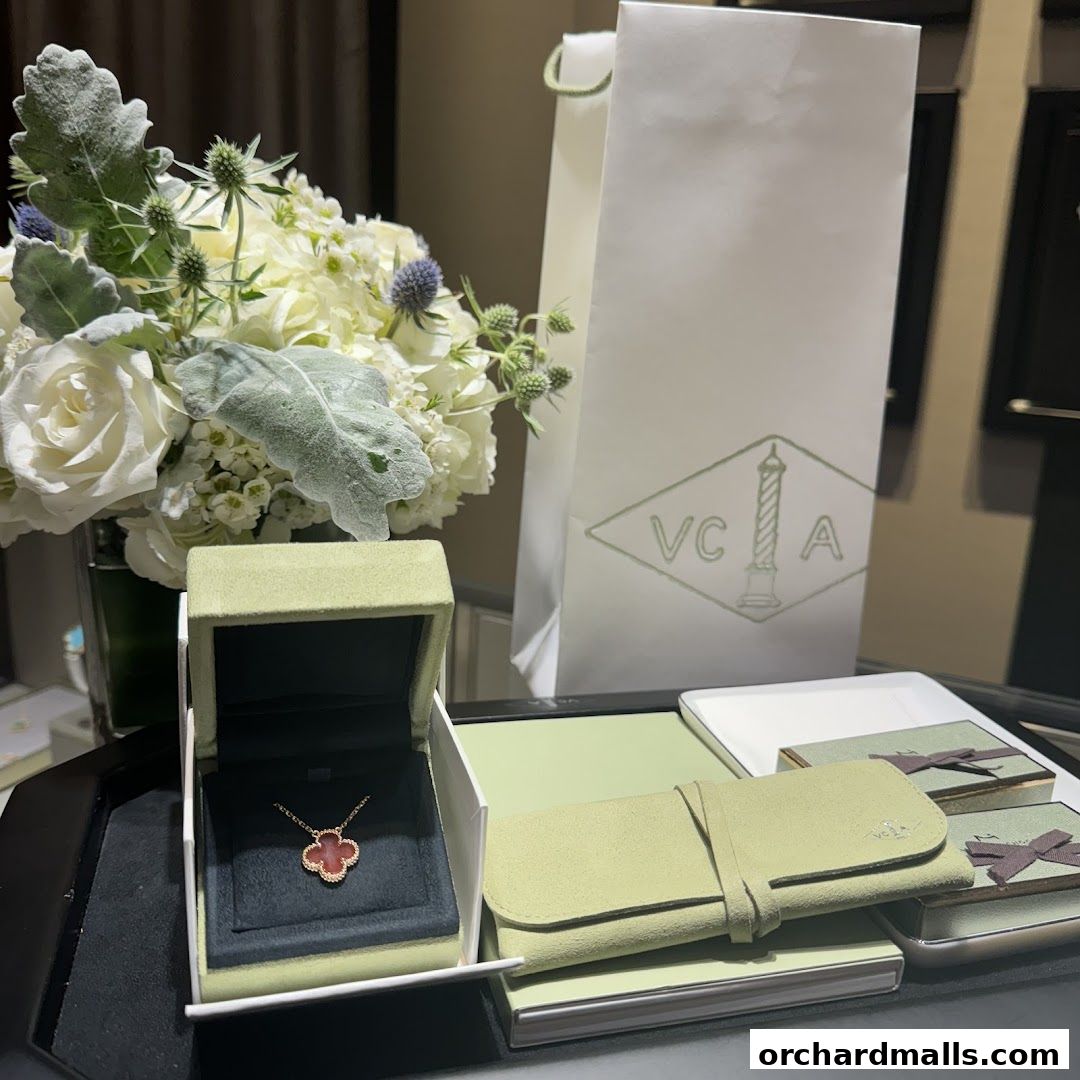 Van Cleef & Arpels necklace in its box, with a bouquet and shopping bag.