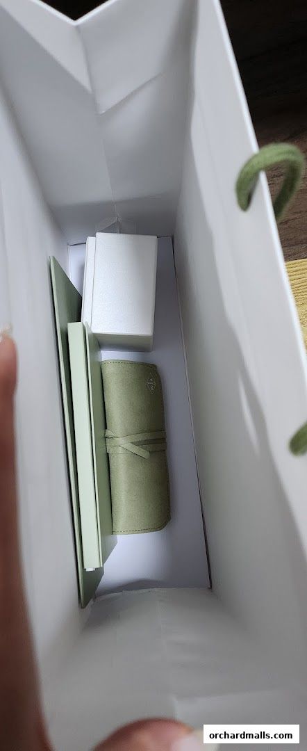 Inside a Van Cleef & Arpels shopping bag with a small green pouch and white boxes.