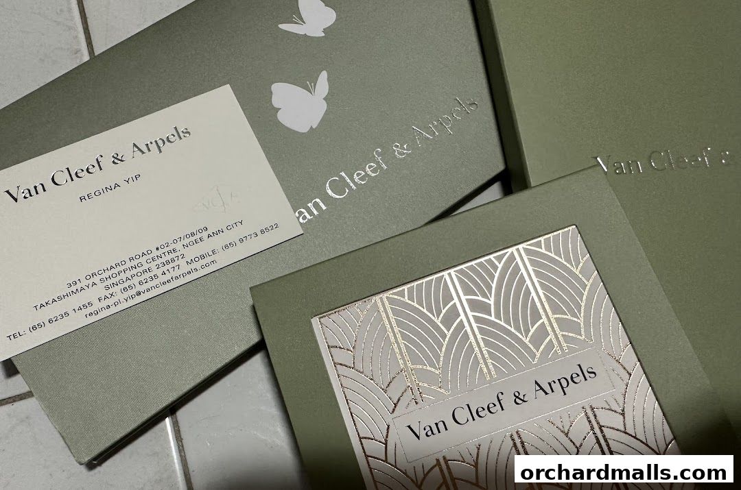 Van Cleef & Arpels gift boxes and a business card with store details.