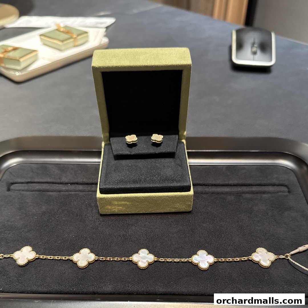 Van Cleef & Arpels earrings and bracelet displayed on a velvet tray.