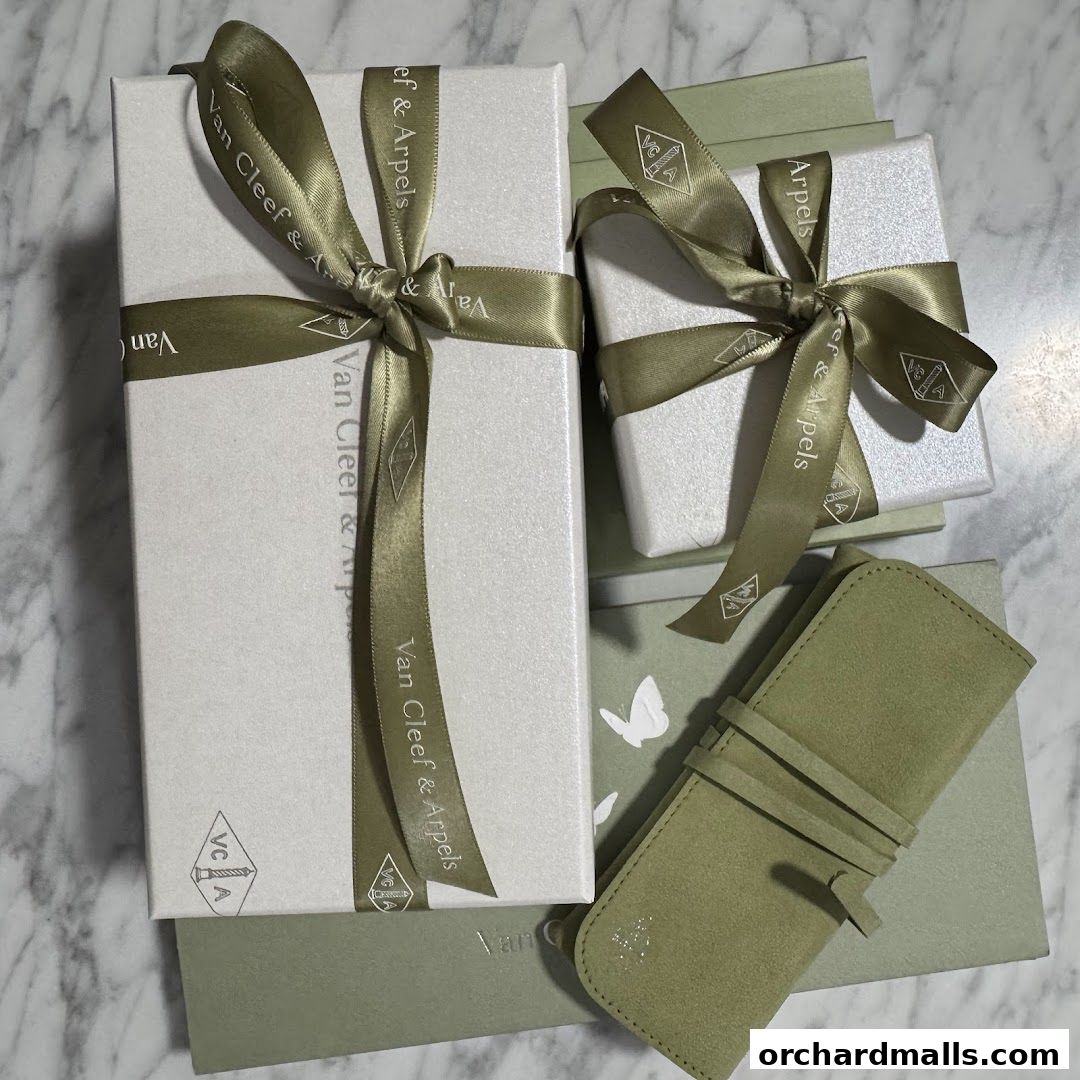 Van Cleef & Arpels gift boxes and a suede pouch on a marble surface.