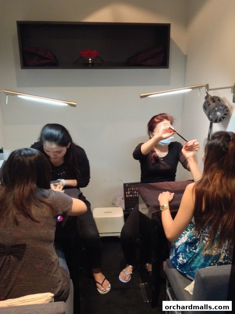 Nail technicians are seen working on clients' nails in a well-lit spa environment.