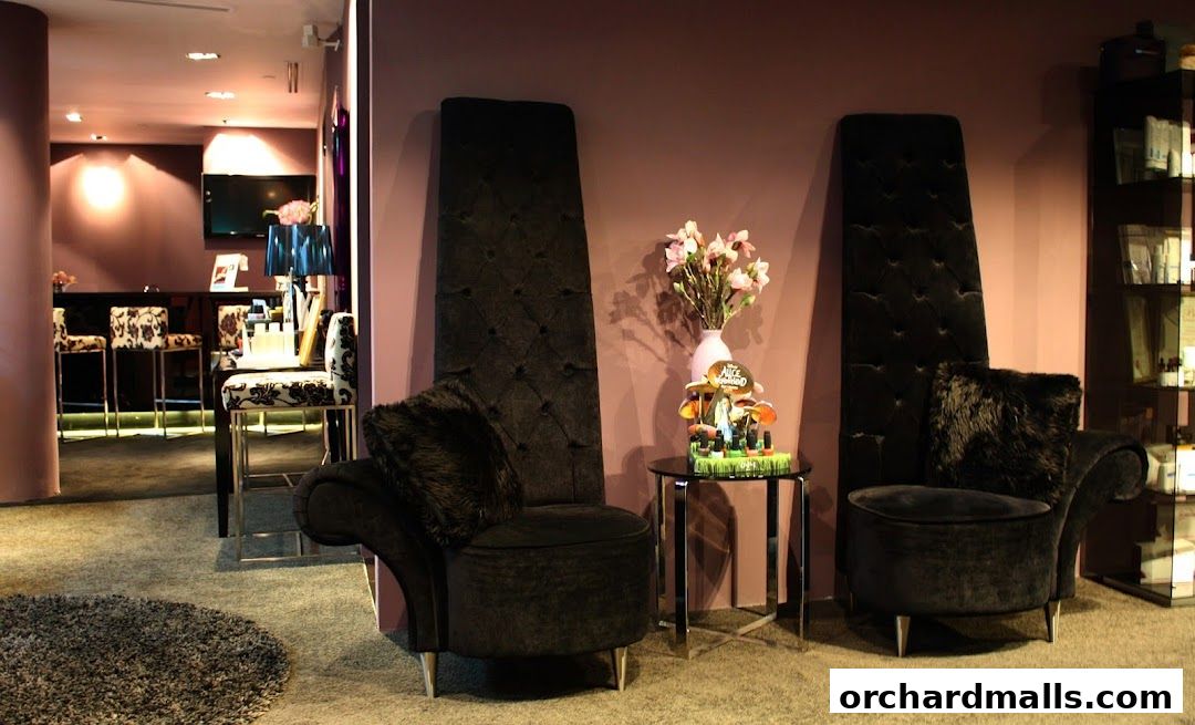 Interior of a medi-spa with plush black chairs, a bar area, and shelves with products.