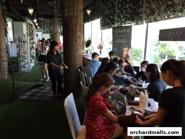 People receiving nail services at Vedure Face, Body & Nail MediSpa with a nature-themed interior.