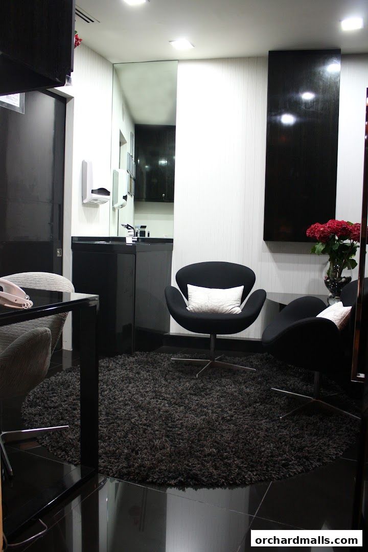 A modern waiting area with black chairs, a dark rug, and a vanity.