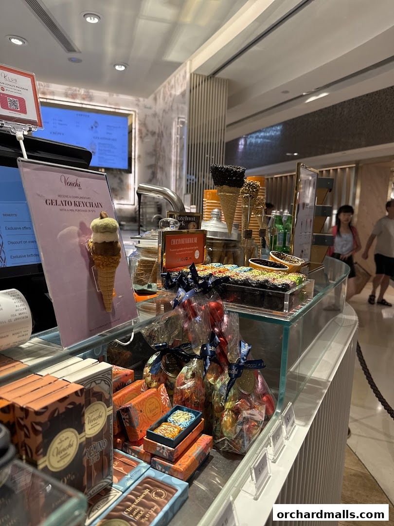 A display of Venchi chocolates and gelato, with promotional signage and customers in the background.