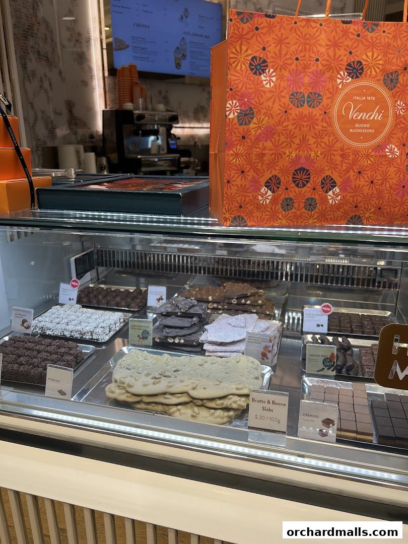 A display case filled with various Venchi chocolates and a branded shopping bag.