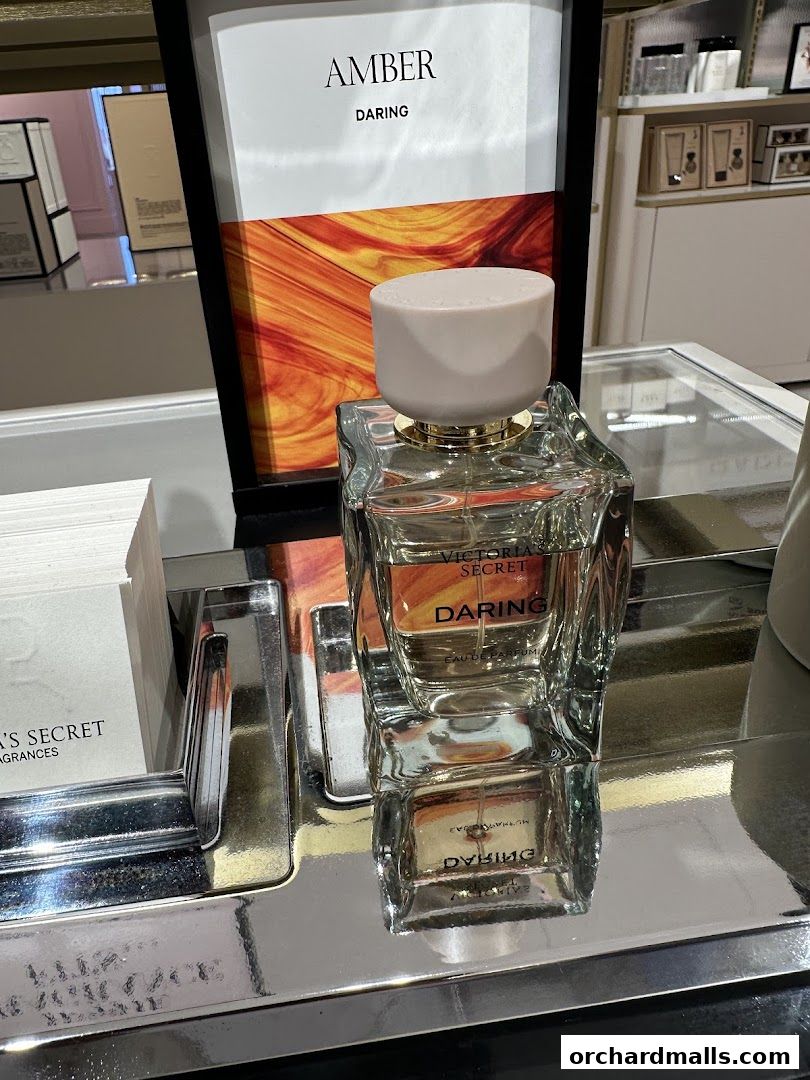 A bottle of Victoria's Secret Daring perfume displayed with a marketing sign.