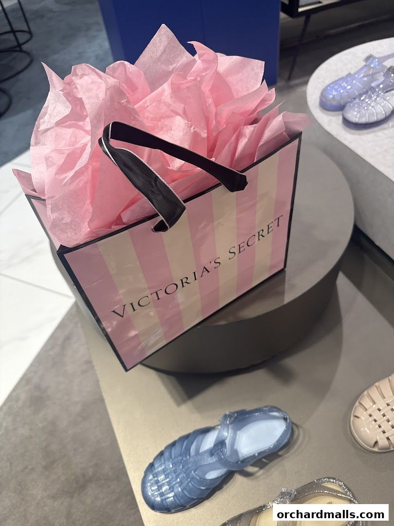 A Victoria's Secret shopping bag filled with pink tissue paper sits on a display.