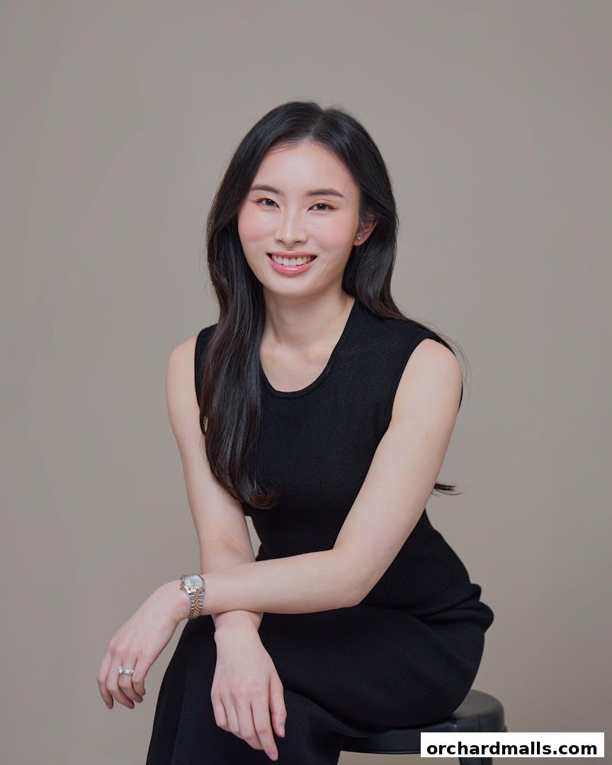 A smiling woman with long dark hair, wearing a black sleeveless top and jewelry.