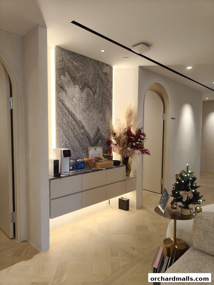 Interior of a modern aesthetic clinic with a reception counter, decorative flowers, and a small Christmas tree.