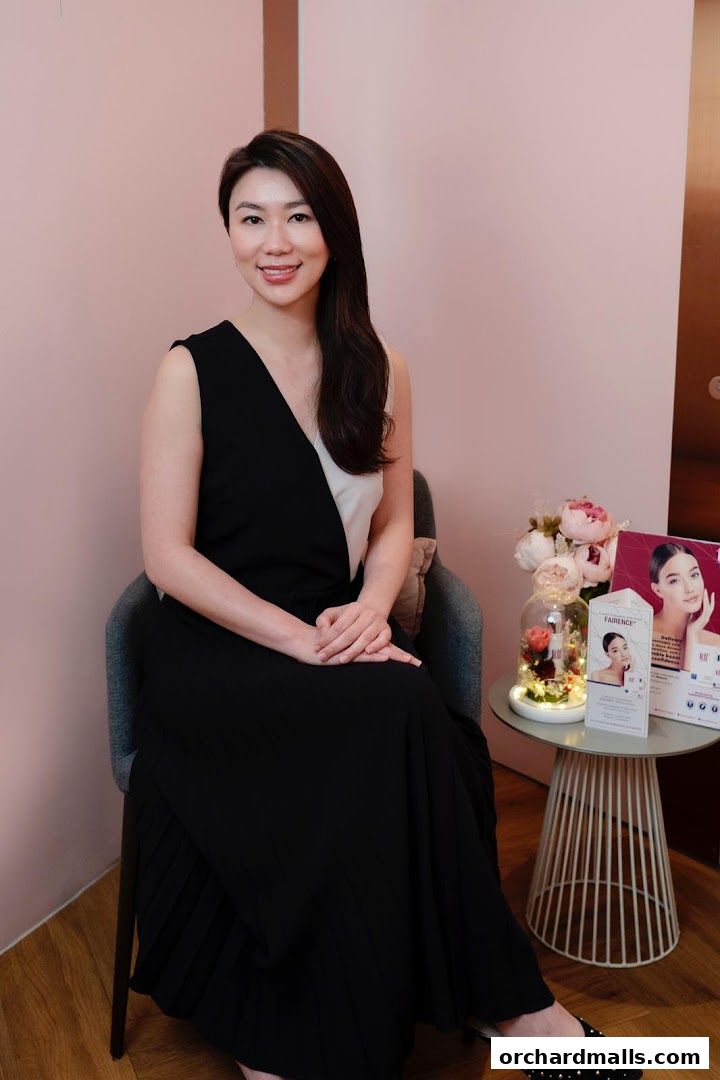 A woman in a black and white dress sits in a chair at a medical aesthetic clinic.