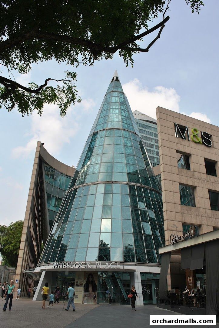 Exterior view of Wheelock Place building with a distinctive glass cone structure and M&S signage.