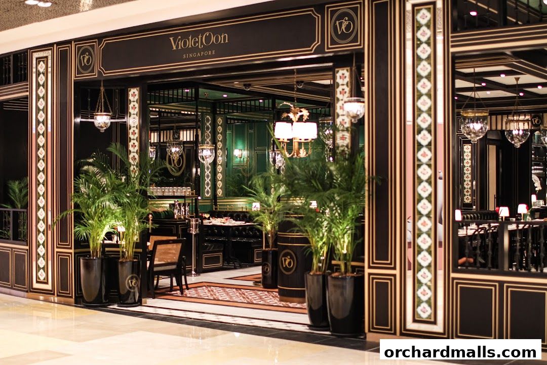 The elegant entrance of Violet Oon Singapore restaurant with lush plants and ornate decor.