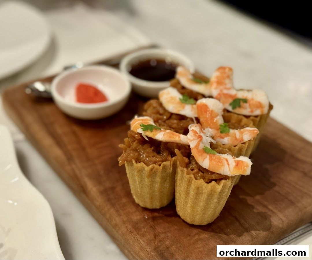A close-up of small tarts filled with savory filling and topped with shrimp.