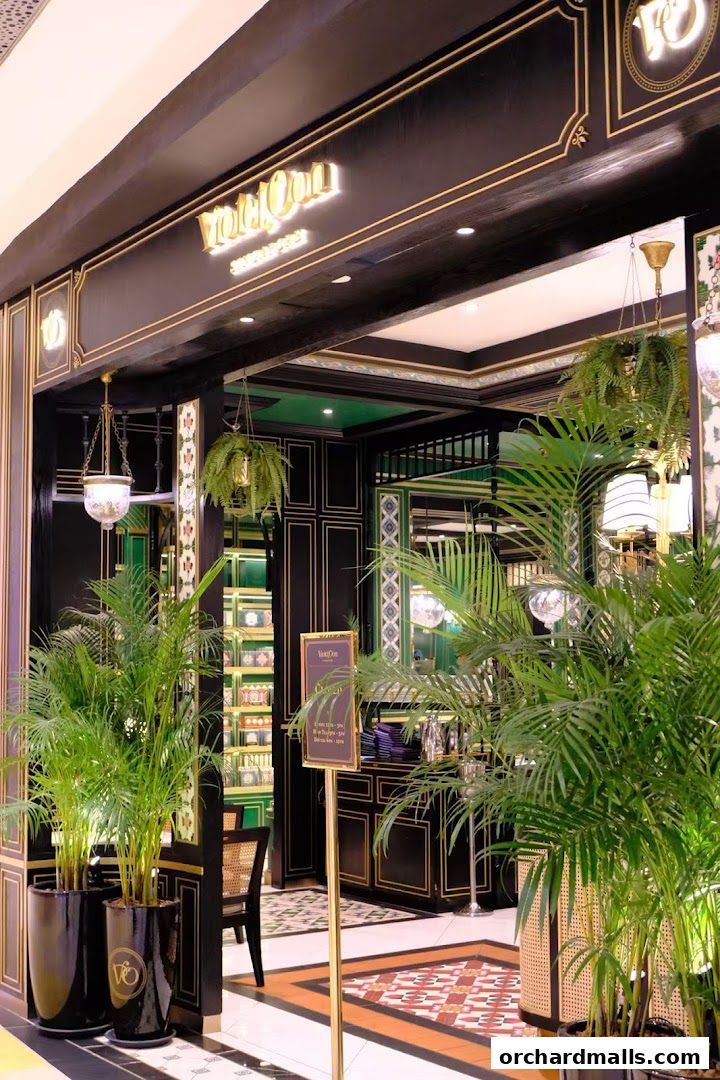 Elegant entrance of Violet Oon restaurant with lush greenery and ornate decor.