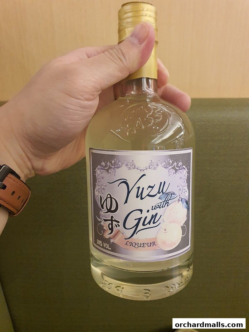A hand holds a bottle of Yuzu with Gin Liqueur.