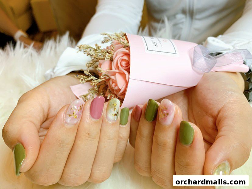 Hands with beautifully manicured nails holding a small bouquet of pink roses.