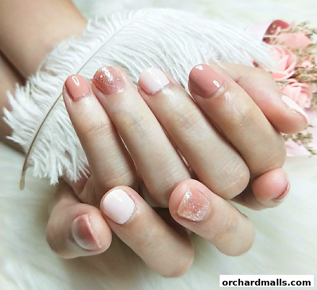 Close-up of hands with elegant, pastel-colored manicured nails and glitter accents.