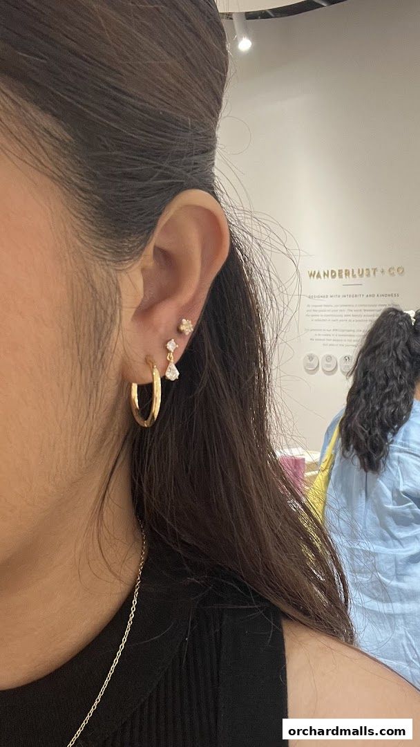 A woman models delicate gold earrings and a necklace from Wanderlust Co.