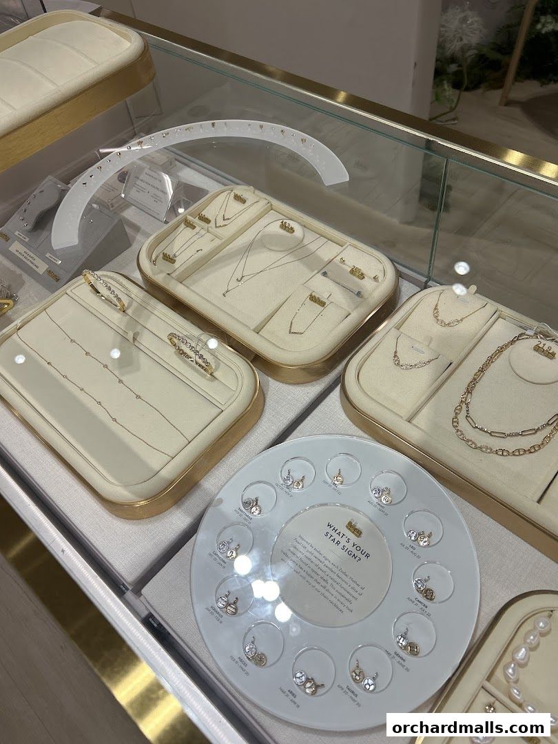 Display case filled with delicate gold necklaces, bracelets, and earrings, featuring zodiac signs.