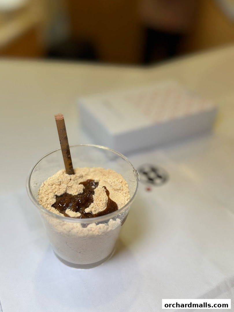 A cup of warabimochi dusted with kinako and drizzled with kuromitsu.