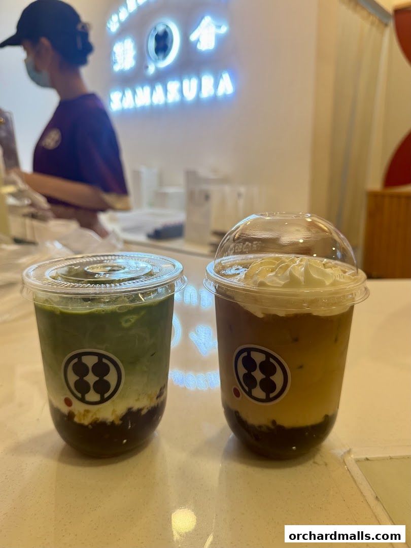 Two delicious drinks, one matcha and one coffee, with whipped cream, sit on a counter.