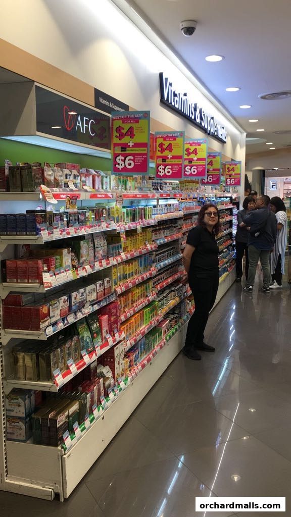 A wide aisle in a Watsons store filled with shelves of vitamins and supplements.