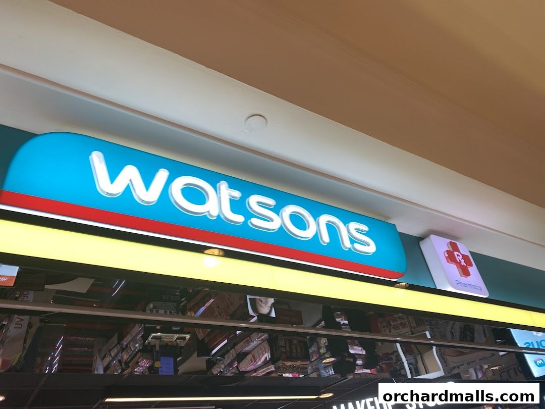 The illuminated Watsons sign and pharmacy symbol above a store entrance.
