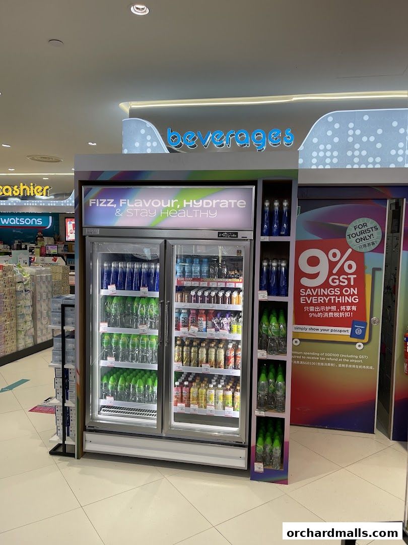 A Watsons store section featuring a refrigerated display of beverages and a promotional sign for tourists.