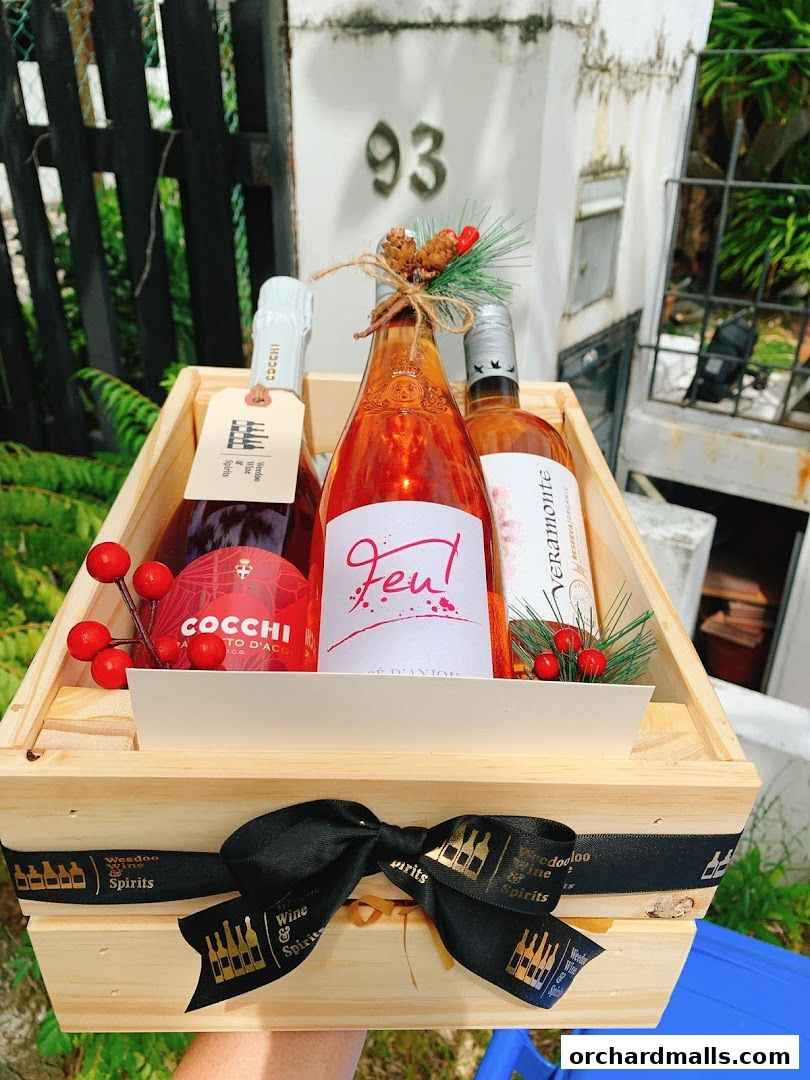 A wooden crate filled with three bottles of wine, decorated for the holidays.