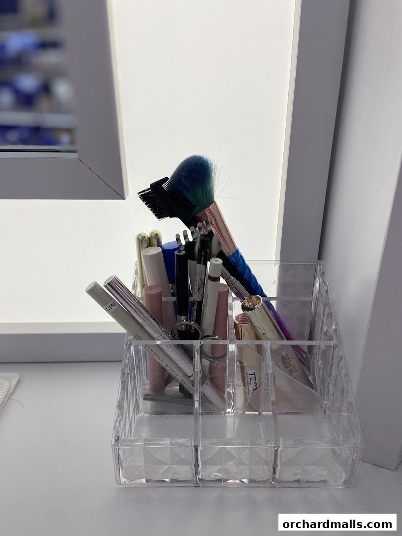 A clear acrylic organizer filled with makeup brushes and cosmetic products.