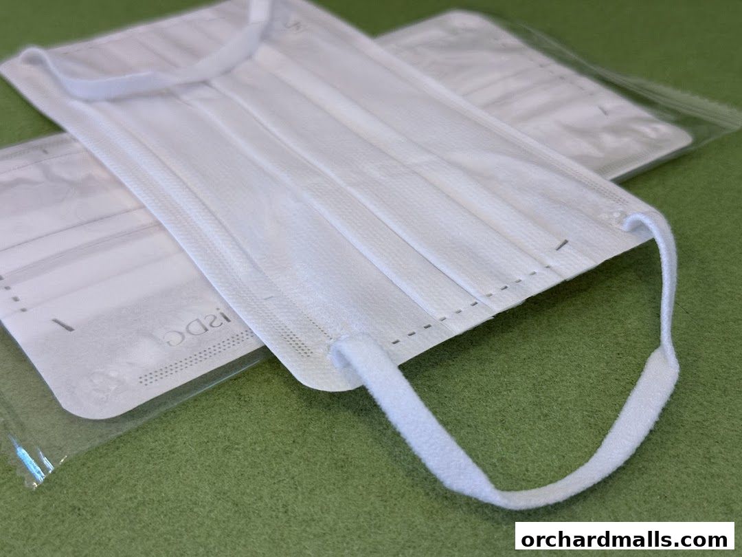 Close-up of white disposable face masks on a green surface.