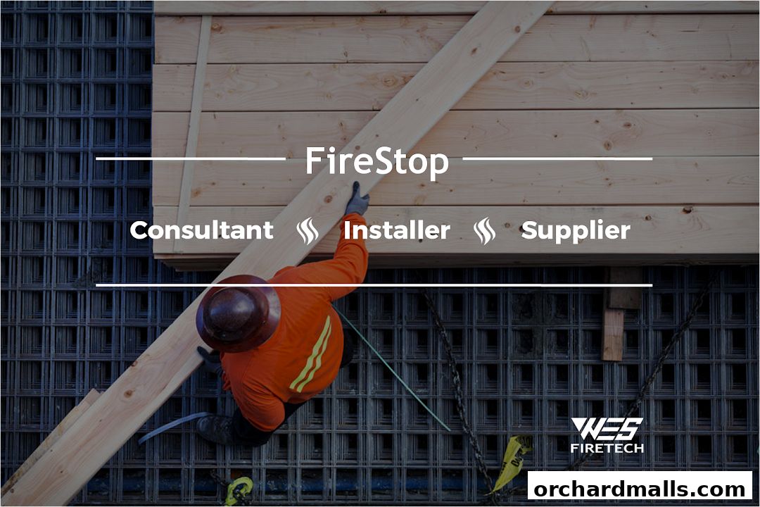 A worker in an orange shirt and hard hat handles lumber, with 'FireStop' text overlay.