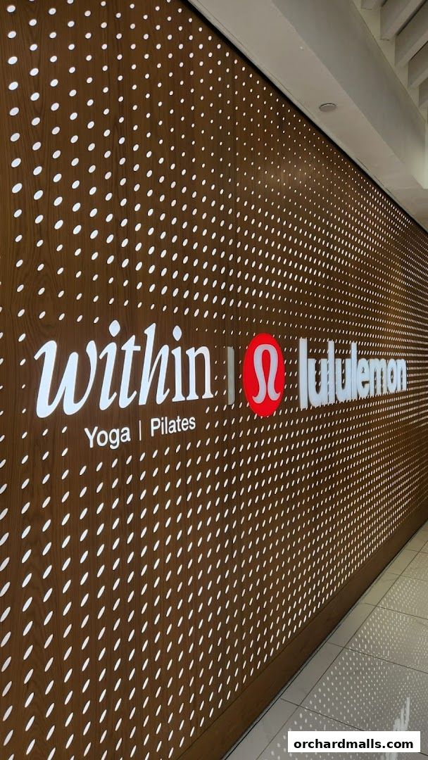 The illuminated logo for Within Yoga Pilates and Lululemon on a patterned wall.