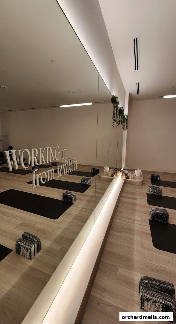 Interior of a yoga and pilates studio with mats, blocks, and motivational text on the mirror.