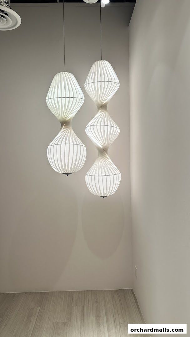 Modern white pendant lights hang in a minimalist room with light wood flooring.