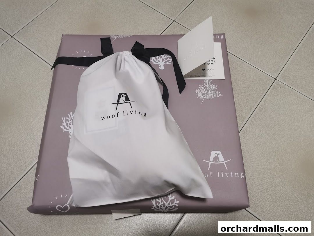 A gift-wrapped package with a white drawstring bag from Woof Living.