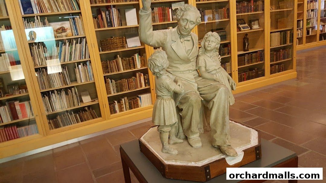 A statue of Hans Christian Andersen reading to children in front of bookshelves.