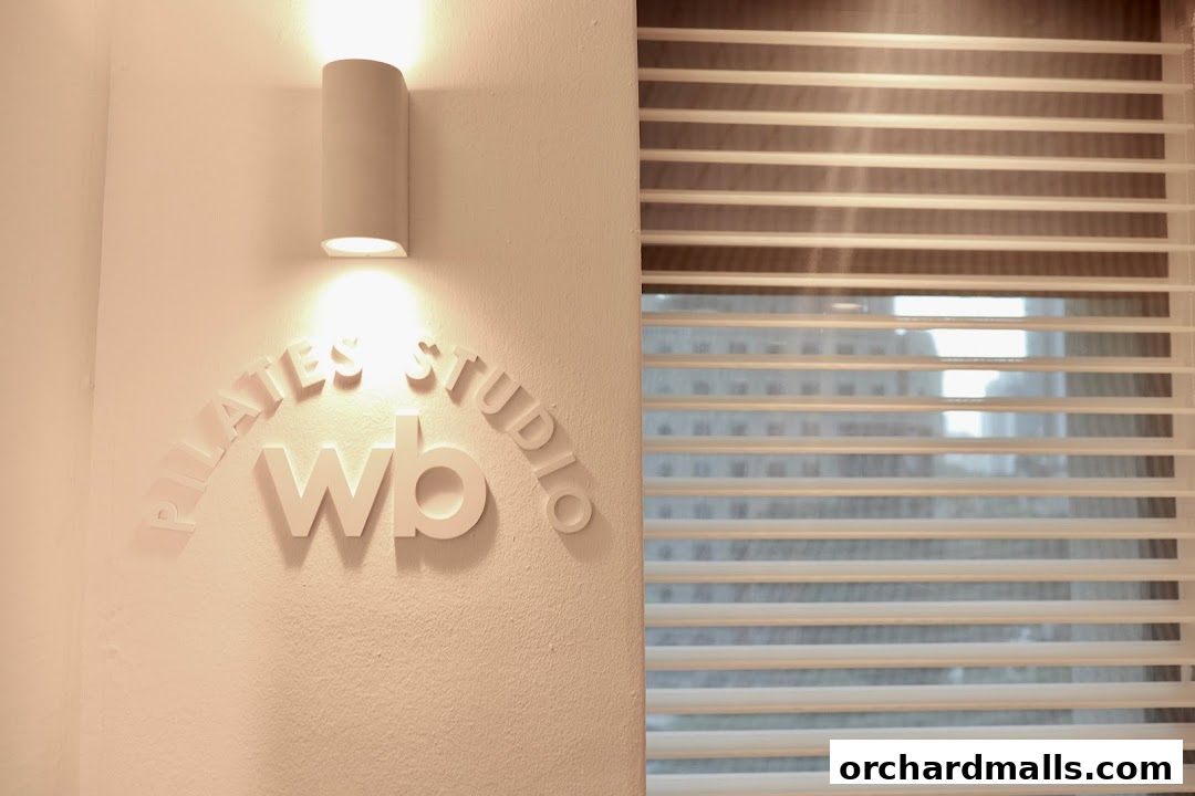 A white 3D logo for Wunderbody Pilates Studio is mounted on a wall with a light fixture.