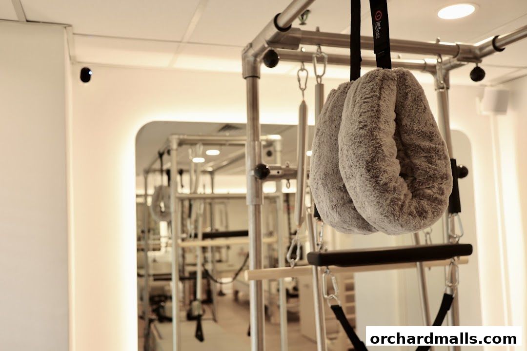 Close-up of a Pilates reformer with plush handles and straps in a bright studio.