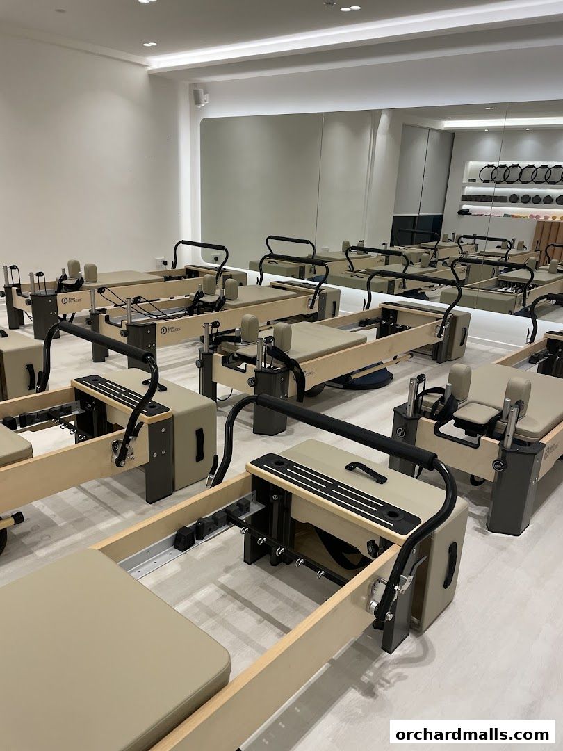 Interior view of a modern Pilates studio with multiple reformers and a large mirror.